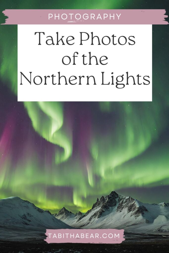 Pin of northern lights dancing over a snow capped mountain.