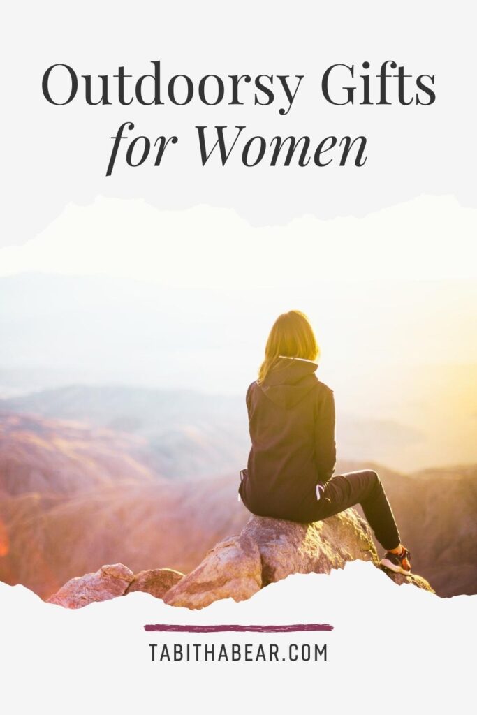 Photo of a woman sitting on a ledge overlooking mountains. Text above reads "Outdoorsy Gifts for Women."