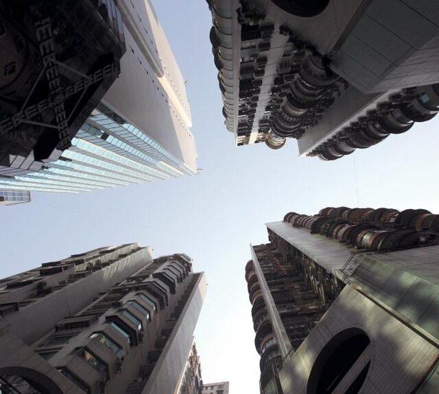 A low-angle view of high-rise buildings that give off a dystopian vibe, an emphasis on Dystopian Romance Novels.