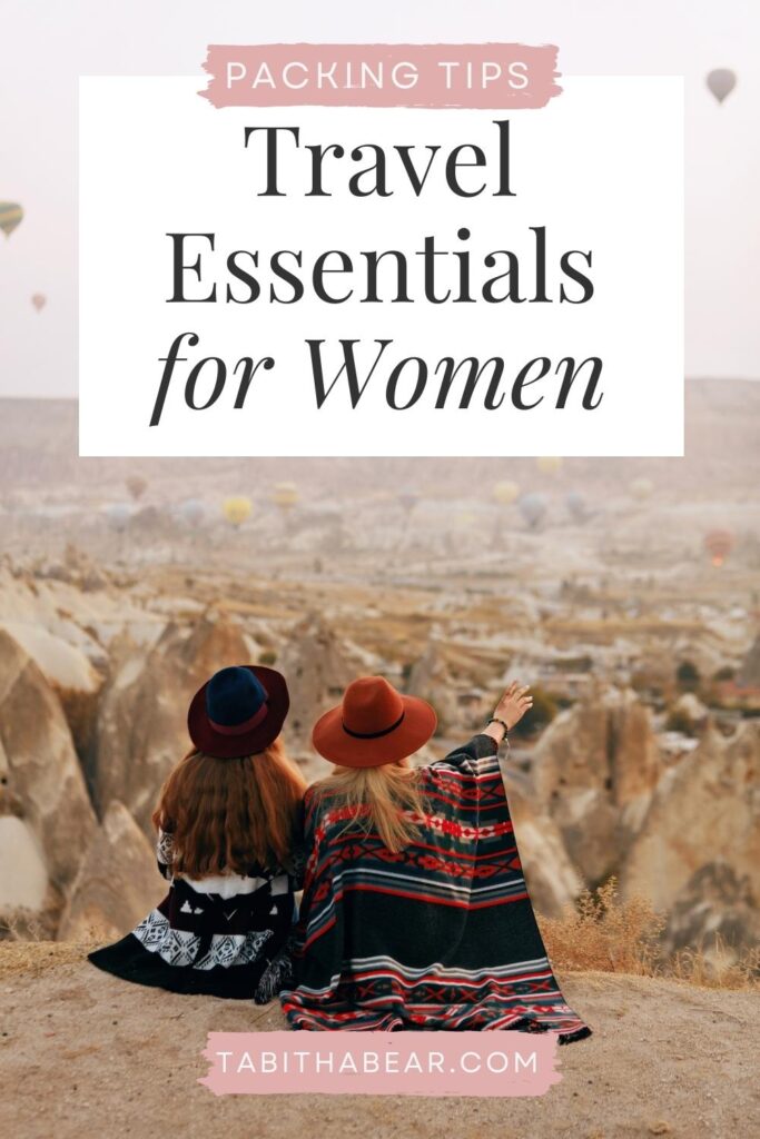 Photo of 2 women sitting on a cliff watching hot air balloons in the distance. Text above the photo reads "Packing Tips: Travel Essentials for Women."